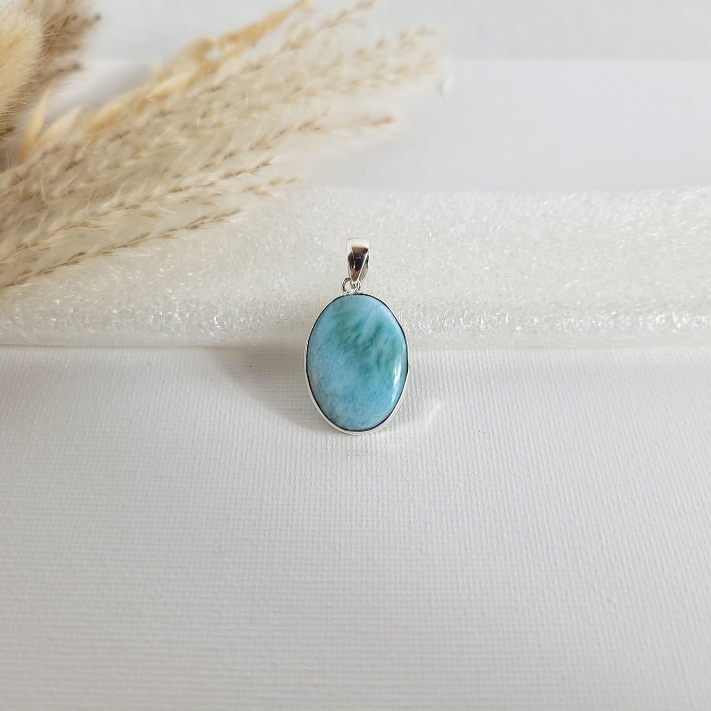 Larimar Kettenanhänger in 925er Silberfassung, 2,3 x 1,7 cm, mit hellblauen und weißen Farbverläufen, fotografiert vor neutralem Hintergrund.