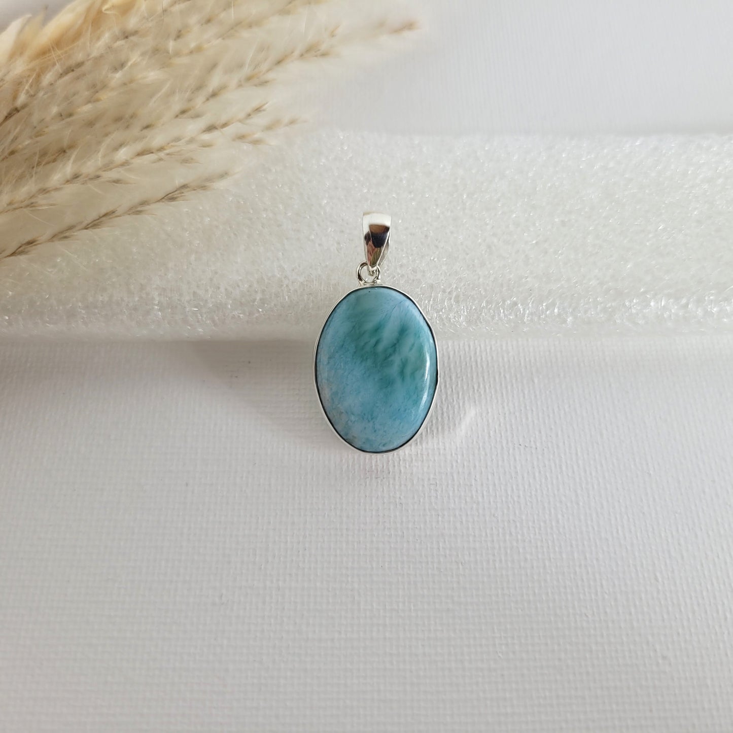 Larimar Kettenanhänger in 925er Silberfassung, 2,3 x 1,7 cm, mit hellblauen und weißen Farbverläufen, fotografiert vor neutralem Hintergrund.