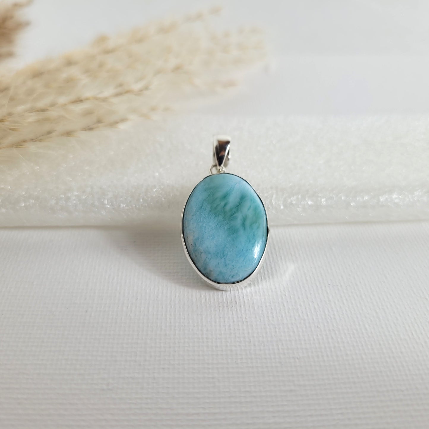 Larimar Kettenanhänger in 925er Silberfassung, 2,3 x 1,7 cm, mit hellblauen und weißen Farbverläufen, fotografiert vor neutralem Hintergrund.