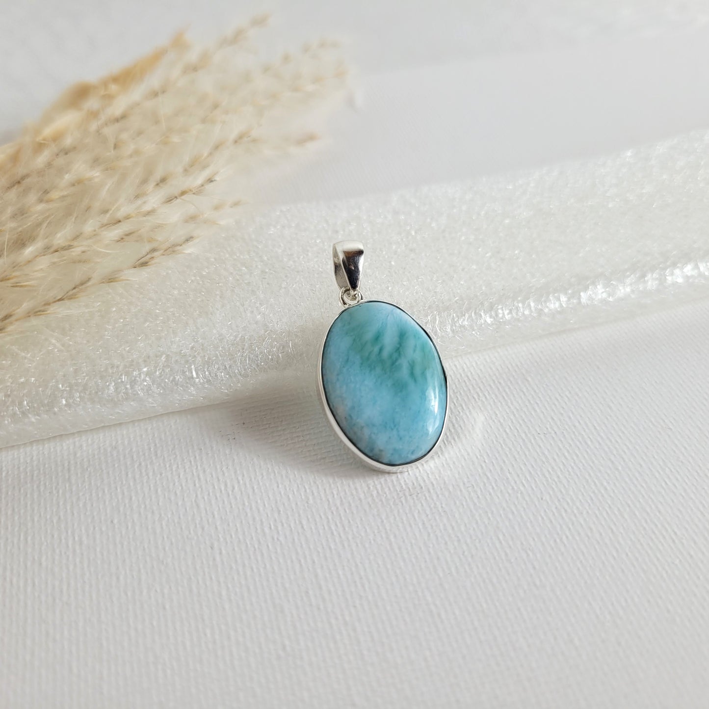 Larimar Kettenanhänger in 925er Silberfassung, 2,3 x 1,7 cm, mit hellblauen und weißen Farbverläufen, fotografiert vor neutralem Hintergrund.