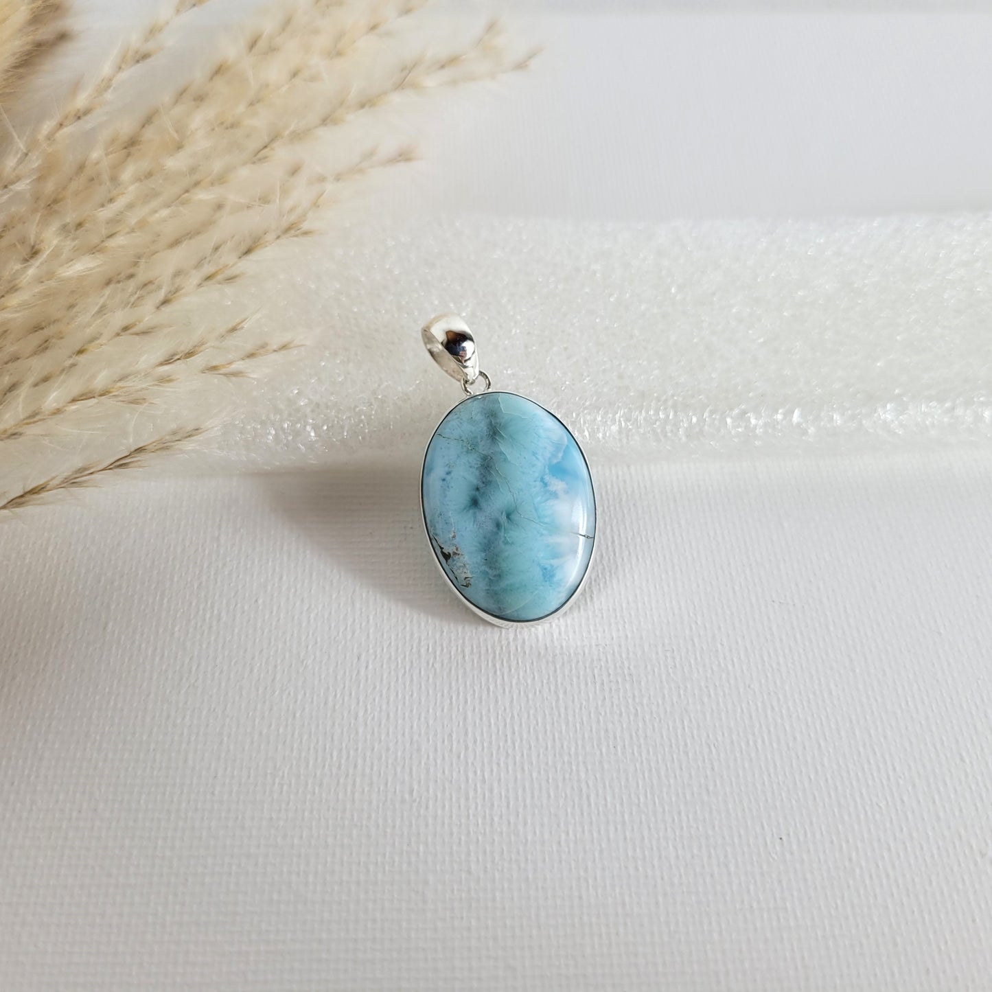 Larimar Kettenanhänger in 925er Silberfassung, 2,6 x 1,9 cm, mit hellblauen und weißen Farbverläufen, fotografiert vor neutralem Hintergrund.