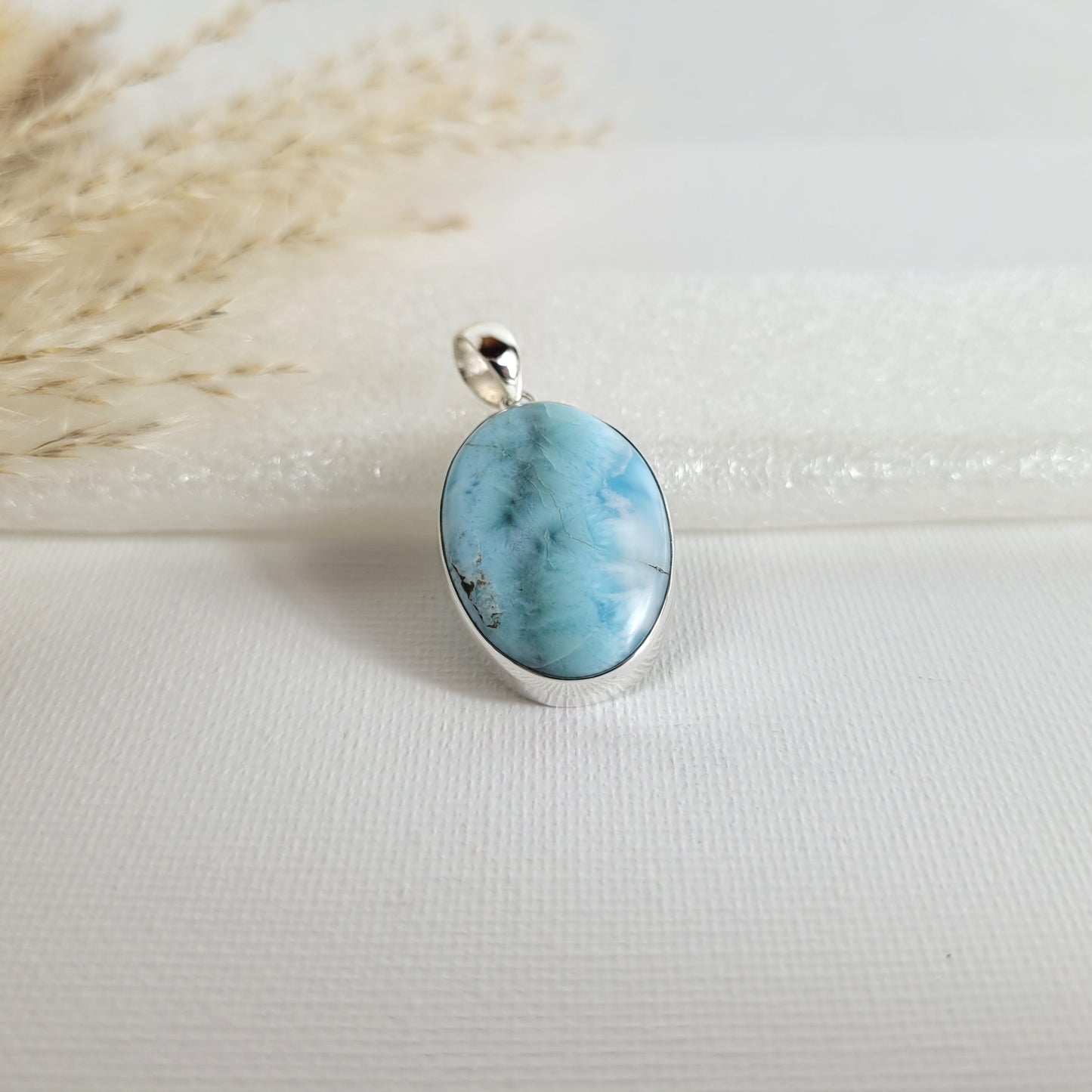 Larimar Kettenanhänger in 925er Silberfassung, 2,6 x 1,9 cm, mit hellblauen und weißen Farbverläufen, fotografiert vor neutralem Hintergrund.
