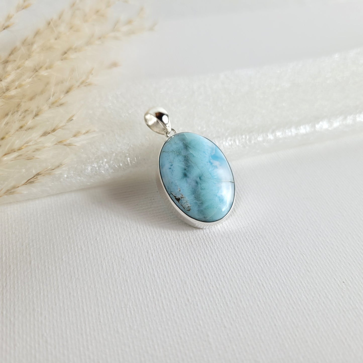 Larimar Kettenanhänger in 925er Silberfassung, 2,6 x 1,9 cm, mit hellblauen und weißen Farbverläufen, fotografiert vor neutralem Hintergrund.