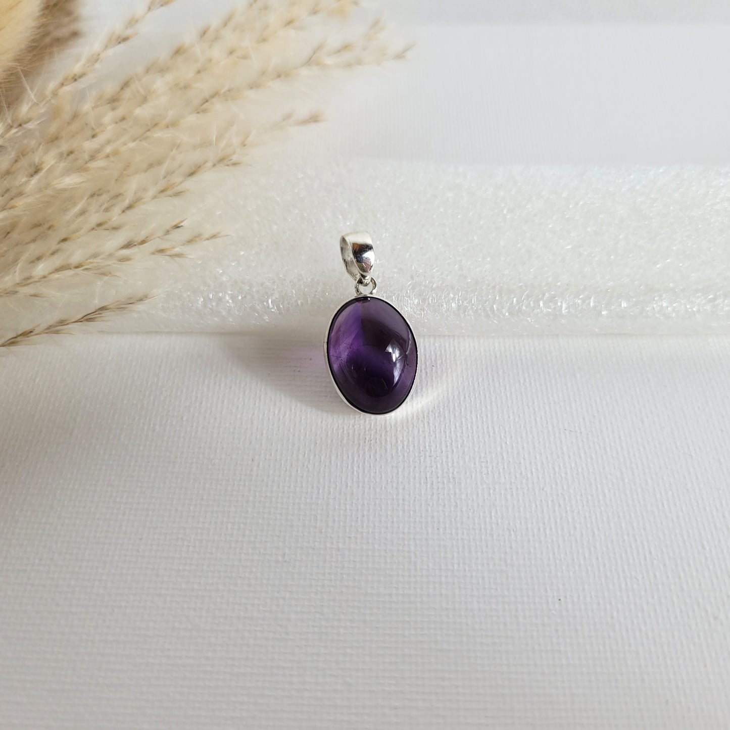 Amethyst Kettenanhänger in 925er Silberfassung, 1,7 x 1,4 cm groß, mit klarer Kristallstruktur und intensiver violetter Farbgebung, fotografiert vor neutralem Hintergrund.