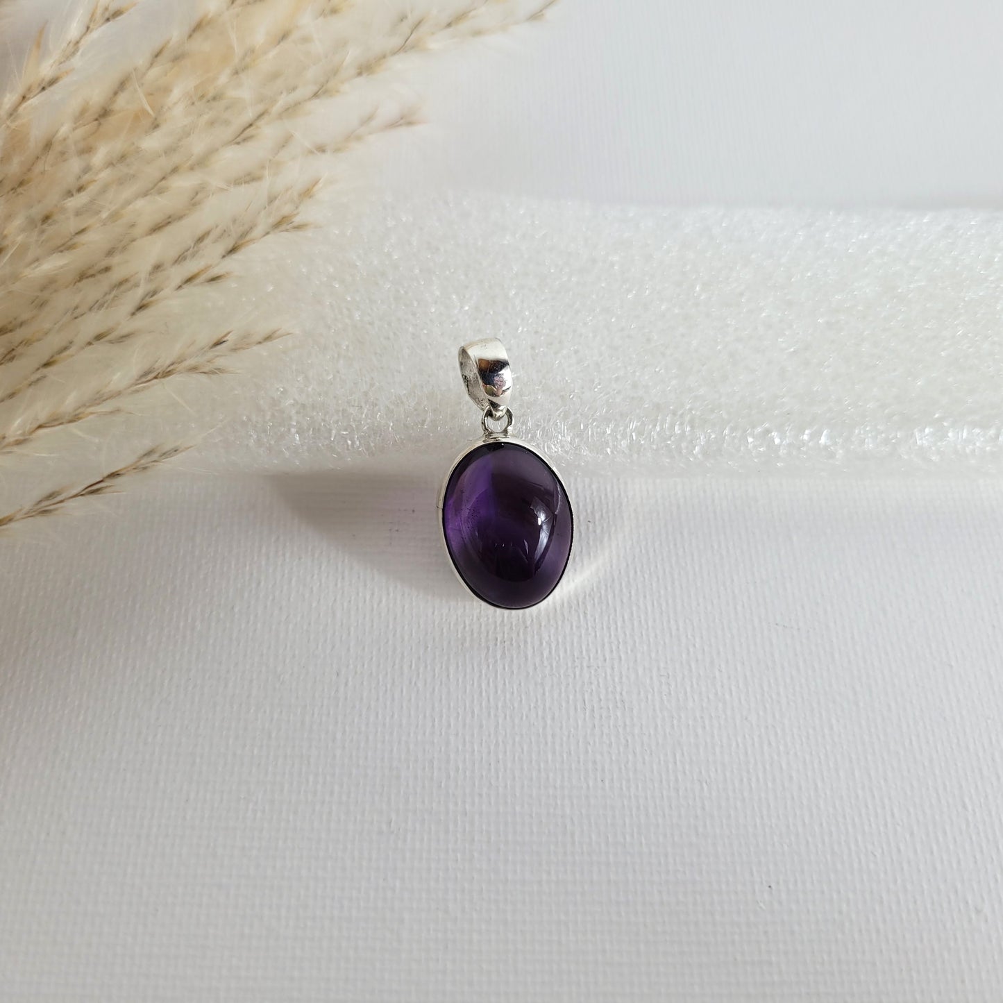 Amethyst Kettenanhänger in 925er Silberfassung, 1,7 x 1,4 cm groß, mit klarer Kristallstruktur und intensiver violetter Farbgebung, fotografiert vor neutralem Hintergrund.