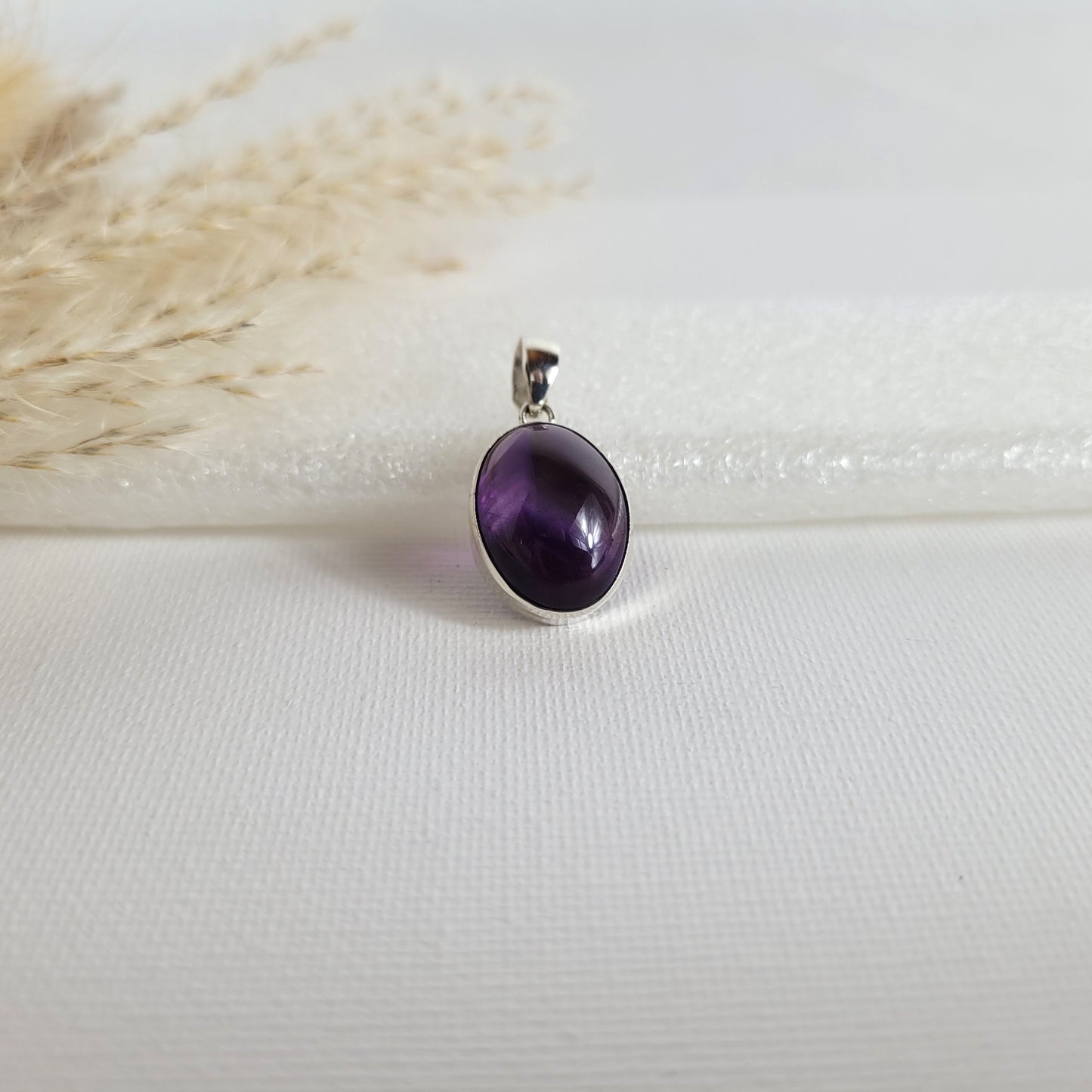 Amethyst Kettenanhänger in 925er Silberfassung, 1,7 x 1,4 cm groß, mit klarer Kristallstruktur und intensiver violetter Farbgebung, fotografiert vor neutralem Hintergrund.