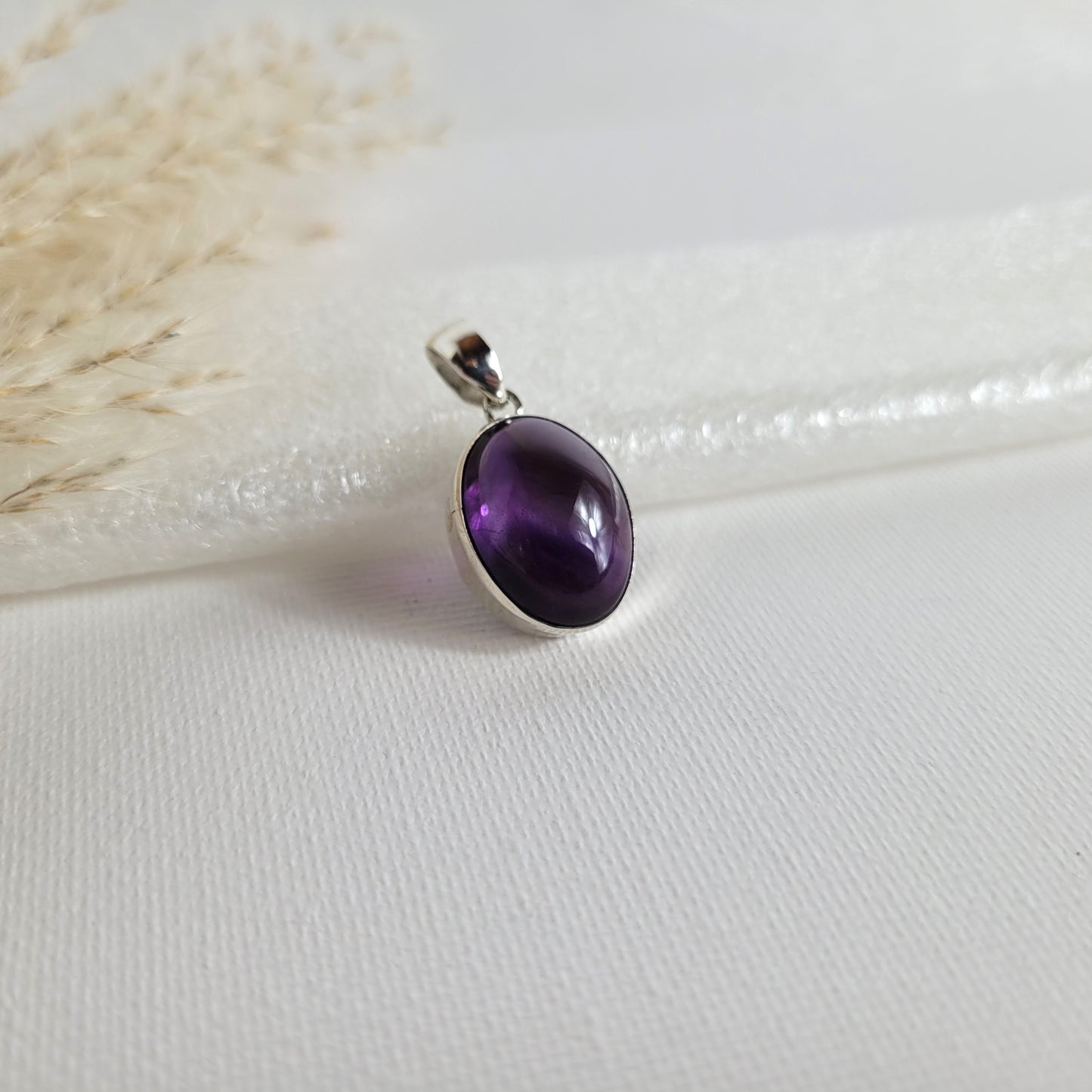 Amethyst Kettenanhänger in 925er Silberfassung, 1,7 x 1,4 cm groß, mit klarer Kristallstruktur und intensiver violetter Farbgebung, fotografiert vor neutralem Hintergrund.