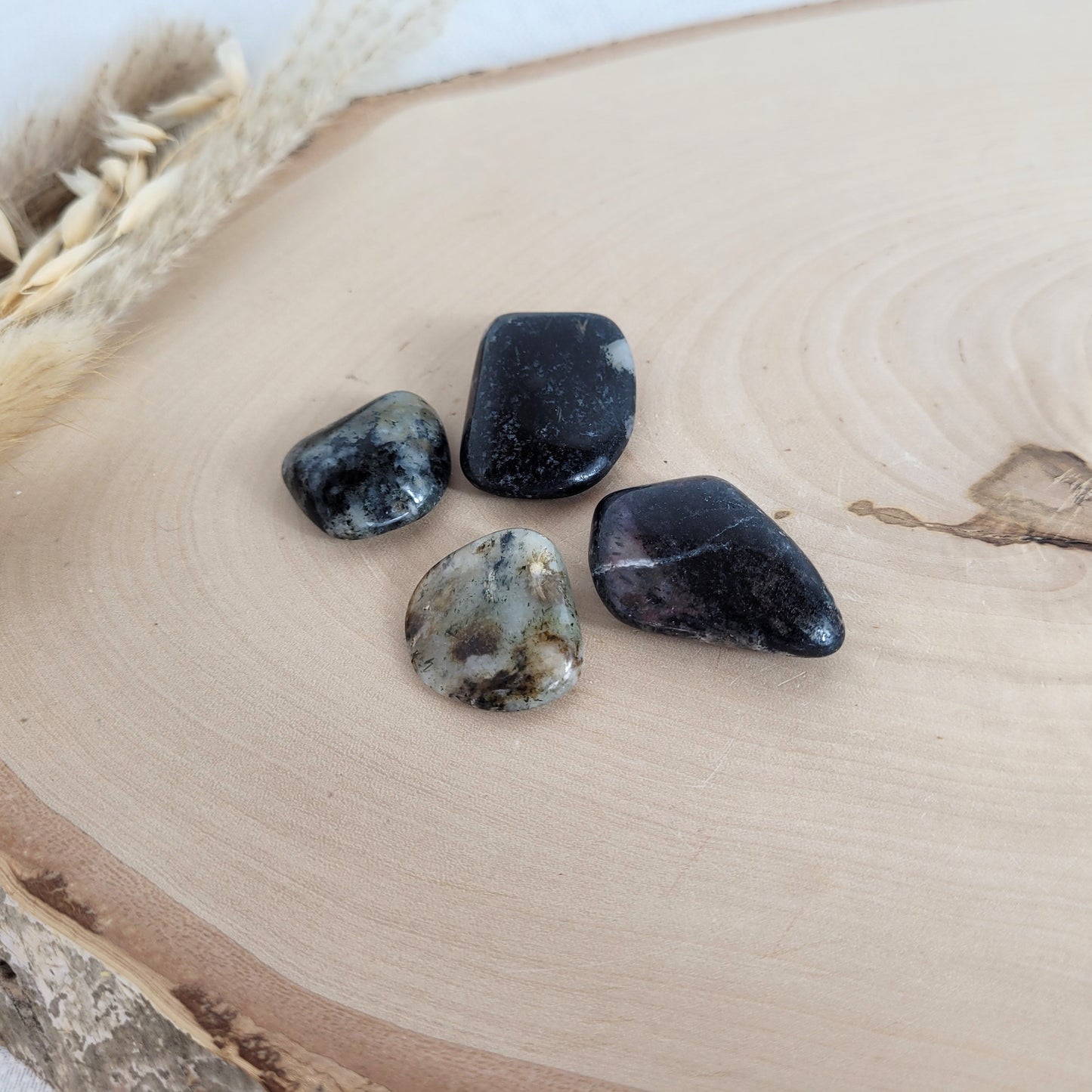 Pegmatit Nephelin-Syenit Trommelstein mit seltenen Mineralien auf einer Holzscheibe fotografiert.
