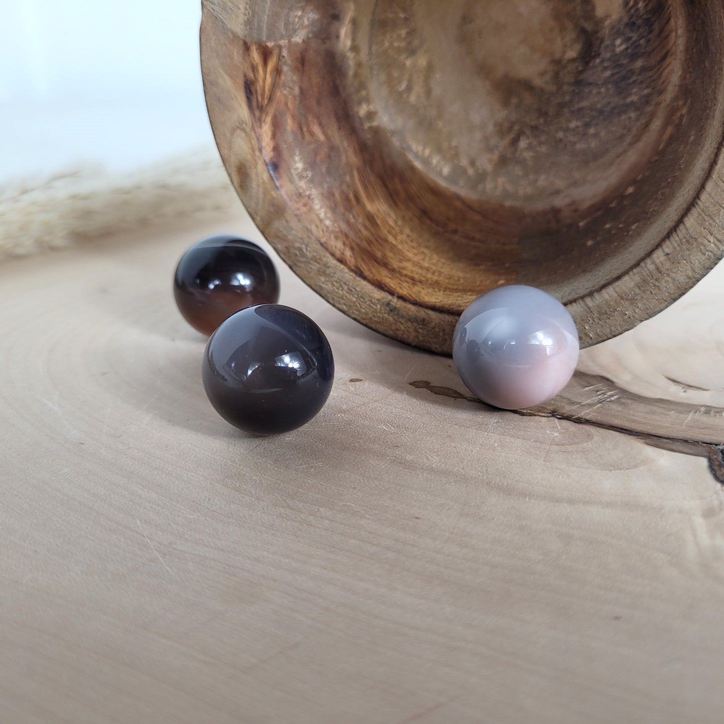 Botswana Achat Kugel Mini mit natürlichen Farben und feinen Bänderungen, präsentiert auf einer runden Holzscheibe zur Hervorhebung der einzigartigen Musterung.