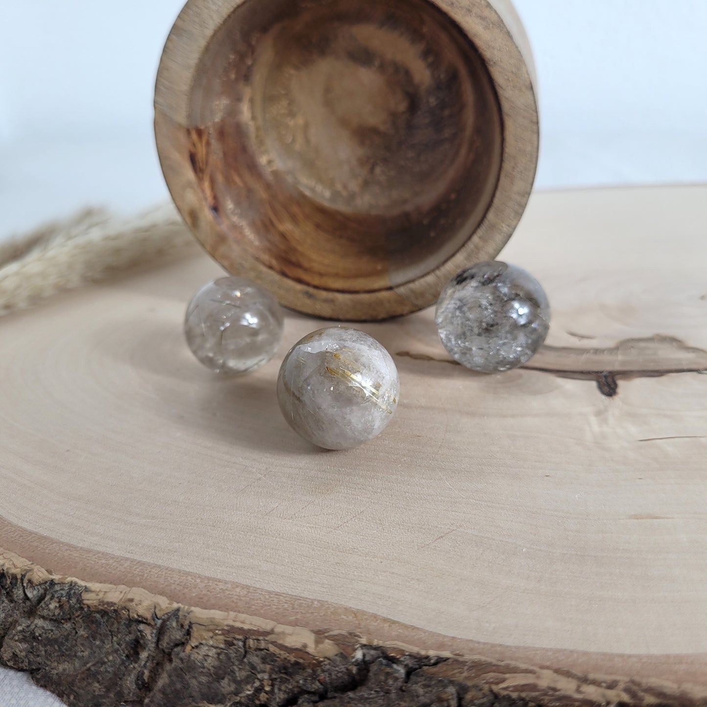 Rutilquarz Kugel mit feinen goldenen Rutil-Einschlüssen auf runder Holzscheibe präsentiert – natürliche Kristallstruktur mit faszinierendem Glanz.