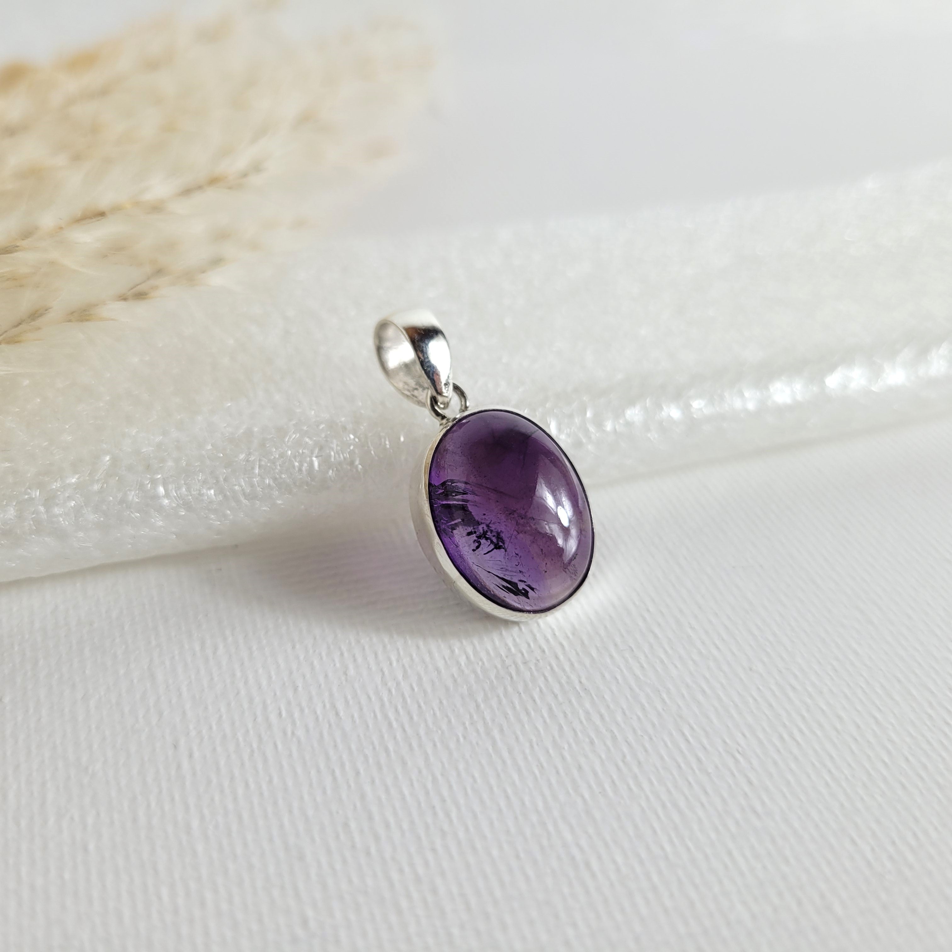 Amethyst Kettenanhänger in 925er Silberfassung, 1,6 x 1,3 cm groß, mit klarer Kristallstruktur und intensiver violetter Farbgebung, fotografiert vor neutralem Hintergrund.
