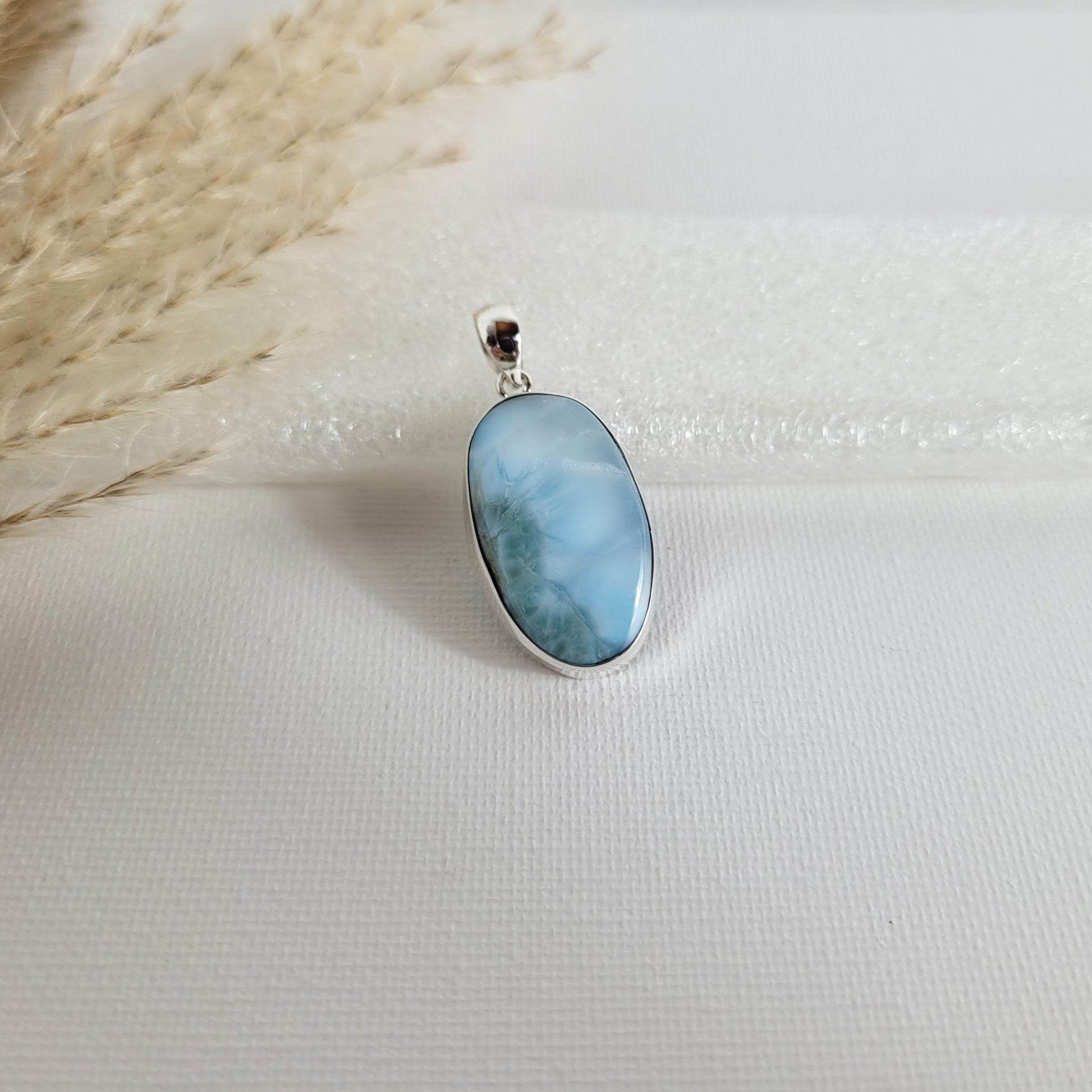 Larimar Kettenanhänger in 925er Silberfassung, 2,6 x 1,7 cm, mit hellblauen und weißen Farbverläufen, fotografiert vor neutralem Hintergrund.