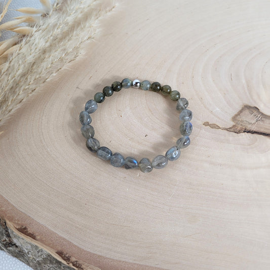 Elastisches Armband mit 6 - 8 mm Labradorit Pebbles und Perlen und Edelstahl Endperle, Holzscheibe als Hintergrund.