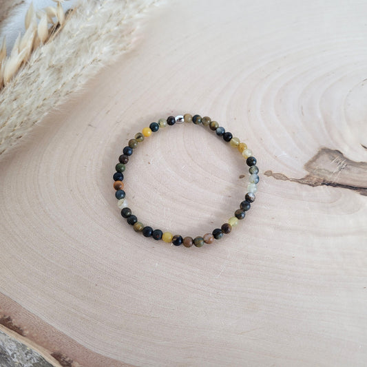 Elastisches Armband mit 4 mm Pietersit Perlen und Edelstahl Endperle, Holzscheibe als Hintergrund.