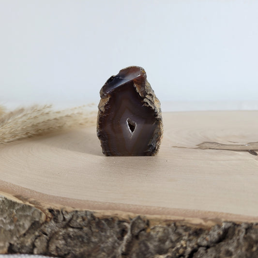 Achat Geode mit natürlicher Kristallöffnung und flacher Standfläche, platziert auf einer Holzscheibe.