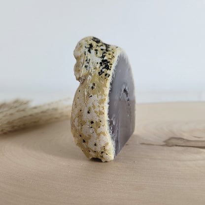 Achat Geode mit natürlicher Kristallöffnung und flacher Standfläche, platziert auf einer Holzscheibe.